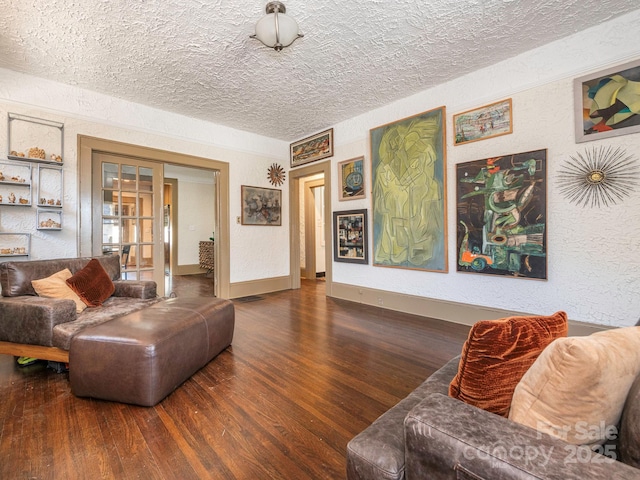 living room with a textured ceiling, a textured wall, wood finished floors, and baseboards