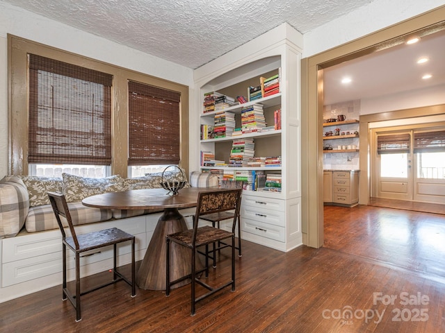 dining space with breakfast area, dark wood finished floors, a textured ceiling, and built in features