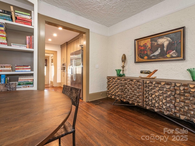 interior space with a textured ceiling, wood finished floors, and a textured wall