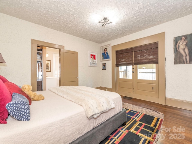 bedroom featuring a textured ceiling, a textured wall, and wood finished floors