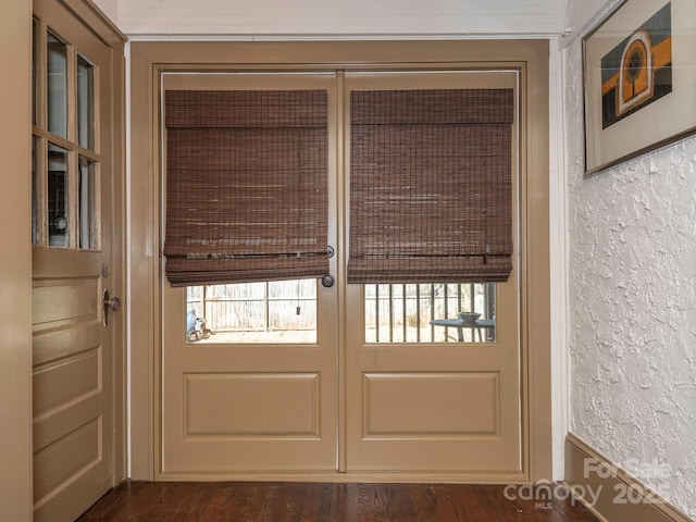 doorway to outside featuring a textured wall and wood finished floors