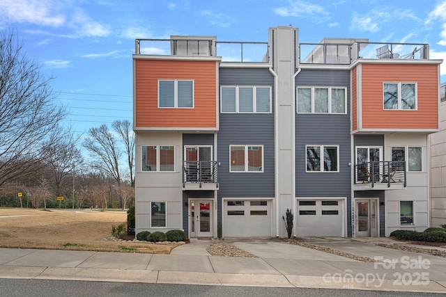 townhome / multi-family property with driveway, an attached garage, and a balcony