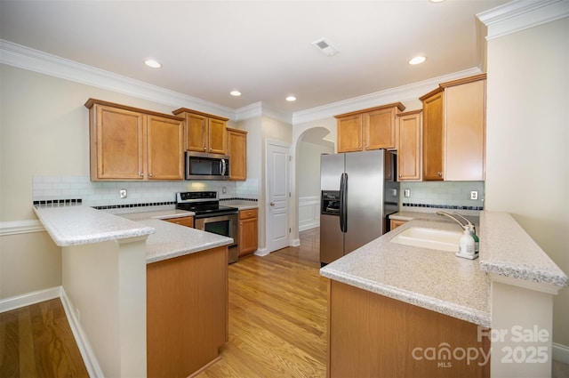 kitchen featuring visible vents, light wood-style flooring, appliances with stainless steel finishes, a sink, and a peninsula