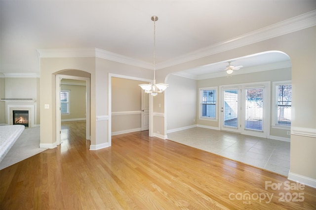 unfurnished dining area featuring wood finished floors, a glass covered fireplace, a ceiling fan, and baseboards