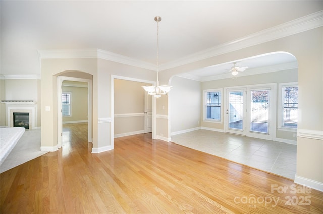 unfurnished dining area featuring baseboards, a glass covered fireplace, light wood-style flooring, and a ceiling fan