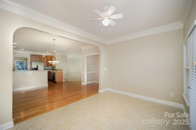 empty room featuring baseboards, arched walkways, light wood-style flooring, and crown molding