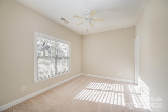 carpeted spare room featuring visible vents, baseboards, and a ceiling fan