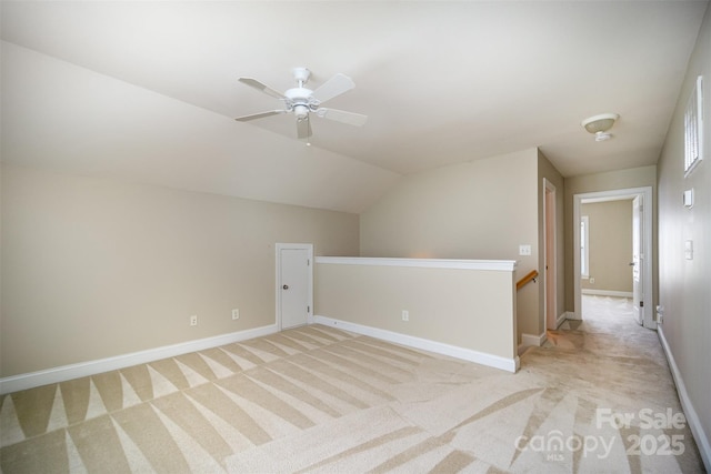 additional living space featuring light carpet, baseboards, vaulted ceiling, and a ceiling fan