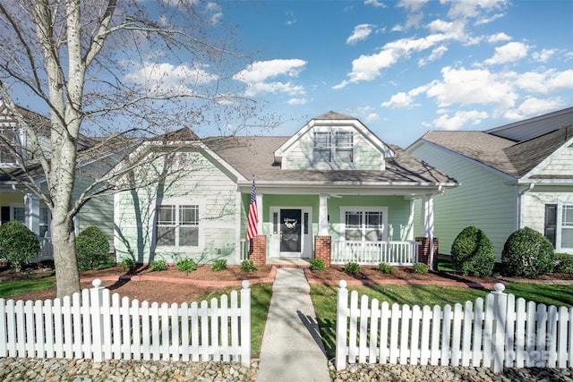 view of front of house with covered porch, brick siding, and a fenced front yard