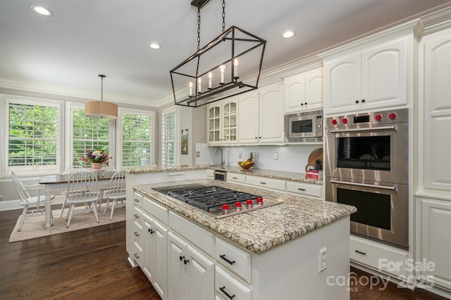 kitchen featuring white cabinets, appliances with stainless steel finishes, light stone countertops, dark wood-type flooring, and ornamental molding