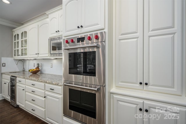 kitchen featuring tasteful backsplash, a sink, beverage cooler, glass insert cabinets, and appliances with stainless steel finishes