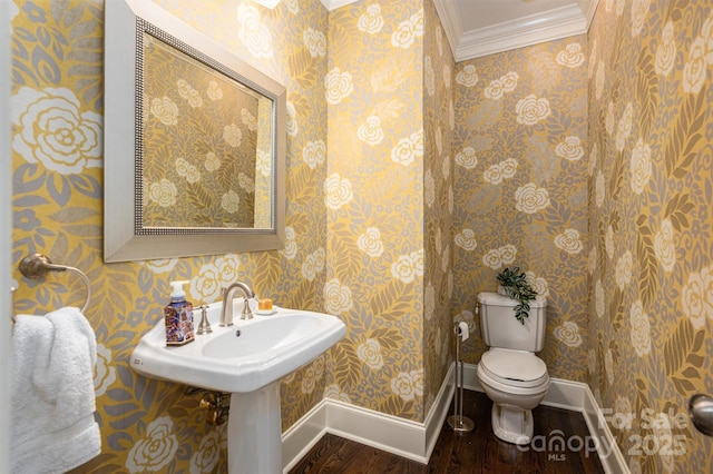 half bath featuring crown molding, toilet, wood finished floors, wallpapered walls, and baseboards