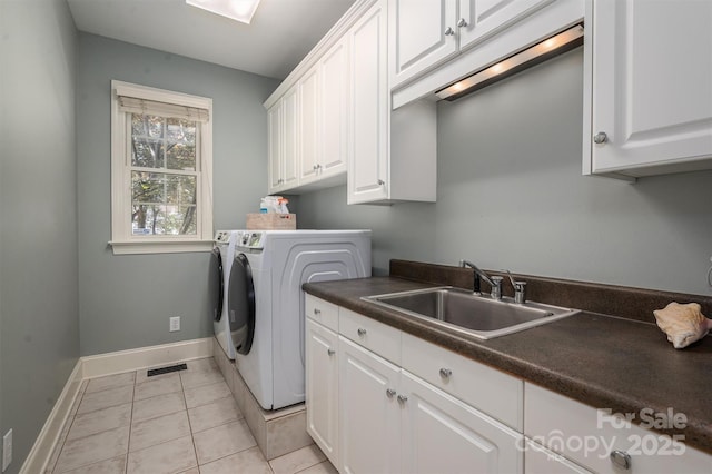 washroom featuring a sink, cabinet space, baseboards, visible vents, and independent washer and dryer