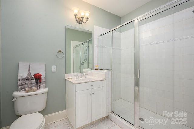 full bath featuring a shower stall, tile patterned floors, vanity, baseboards, and toilet