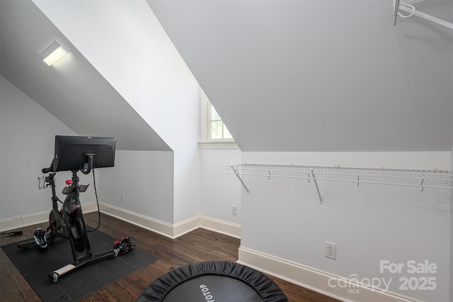 exercise area featuring wood finished floors, lofted ceiling, and baseboards