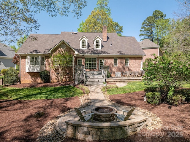 rear view of house with a chimney, a patio area, a wooden deck, a fire pit, and brick siding