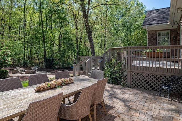 view of patio / terrace with a fire pit, outdoor dining space, and a wooden deck