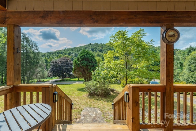 wooden deck with a view of trees and a lawn