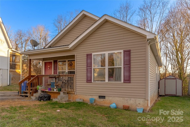 bungalow-style home with an outbuilding, covered porch, crawl space, a shed, and a front lawn