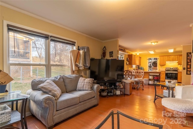 living room featuring ornamental molding, stacked washing maching and dryer, and hardwood / wood-style floors