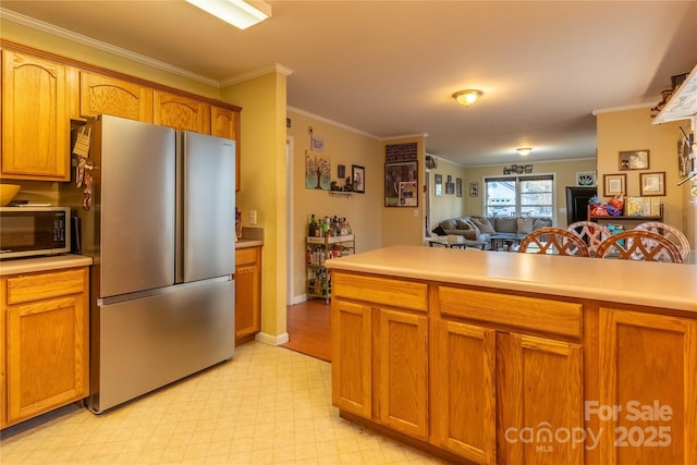 kitchen featuring ornamental molding, light countertops, appliances with stainless steel finishes, and light floors