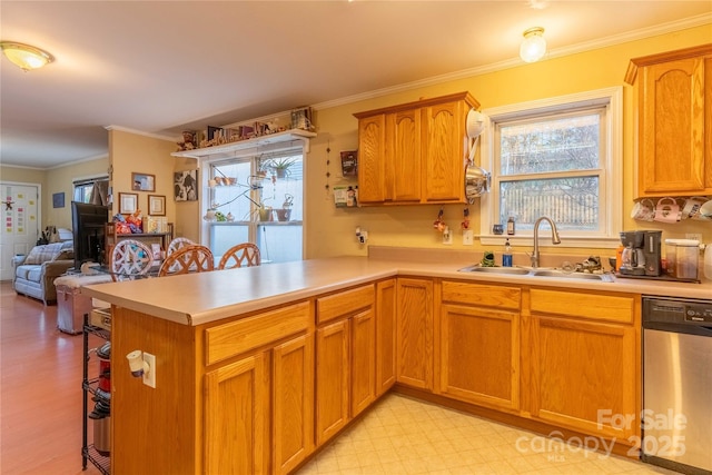 kitchen with light countertops, stainless steel dishwasher, a sink, a peninsula, and a kitchen breakfast bar