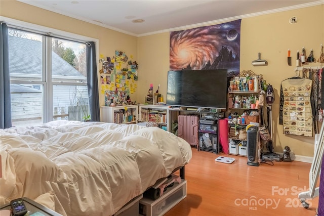 bedroom with ornamental molding and wood finished floors