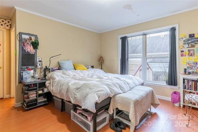 bedroom with baseboards, ornamental molding, and wood finished floors