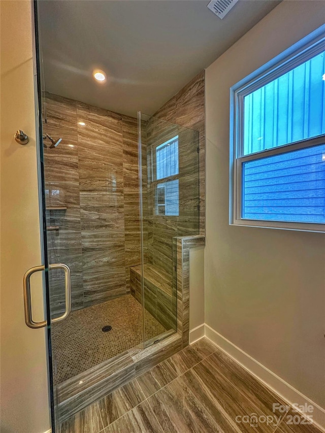 bathroom with a stall shower, visible vents, and baseboards