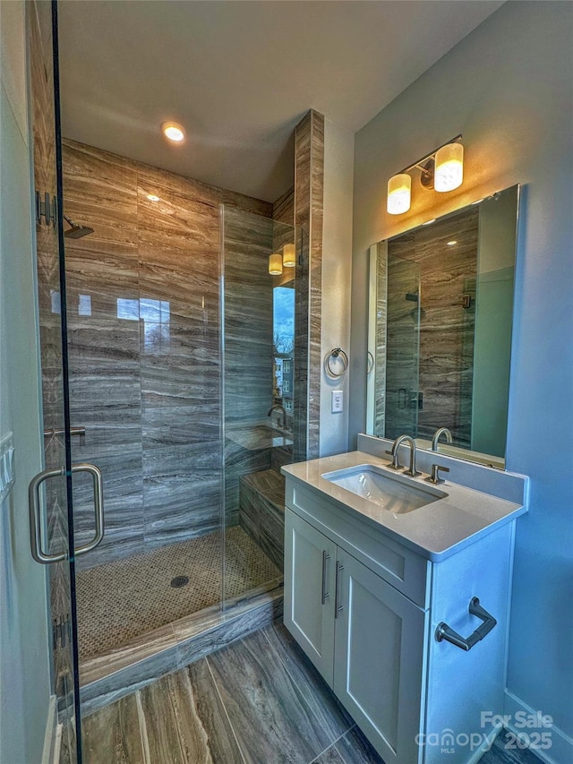 full bathroom featuring a stall shower, vanity, and wood finished floors