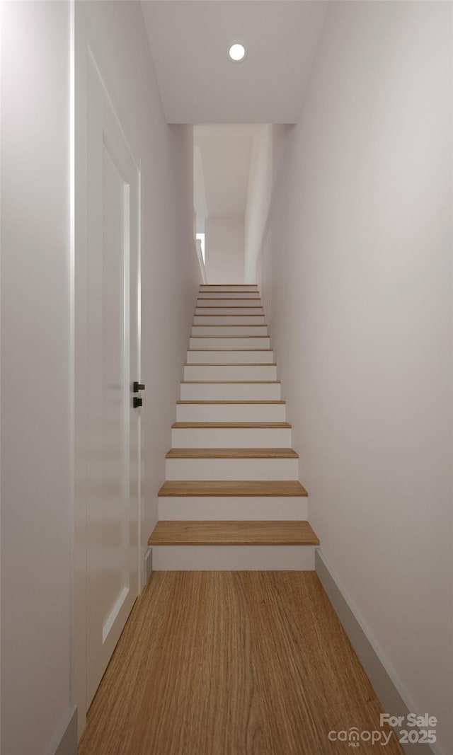 staircase featuring baseboards, wood finished floors, and recessed lighting