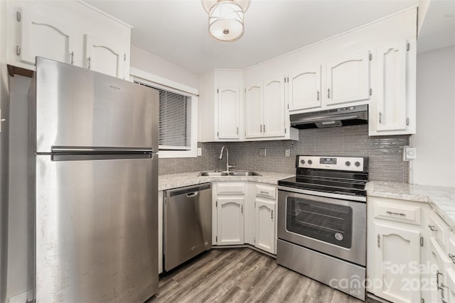 kitchen with stainless steel appliances, light countertops, backsplash, a sink, and under cabinet range hood