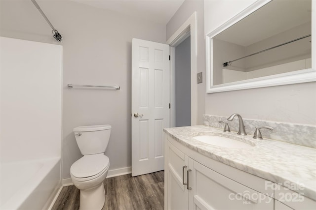 full bath with bathtub / shower combination, toilet, vanity, wood finished floors, and baseboards