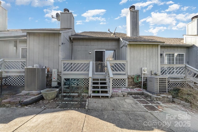 back of property with a shingled roof, a chimney, a wooden deck, and central air condition unit