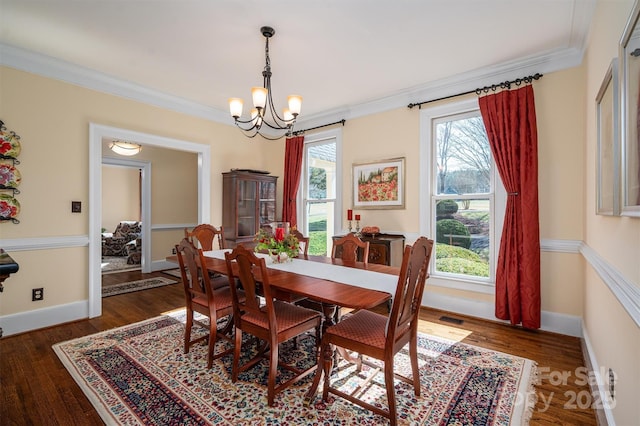 dining area featuring visible vents, an inviting chandelier, ornamental molding, wood finished floors, and baseboards