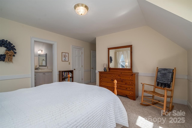 bedroom with ensuite bath, baseboards, vaulted ceiling, and light colored carpet