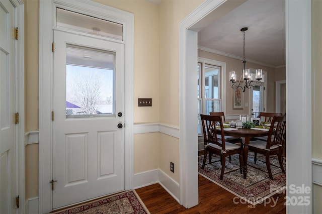 foyer featuring baseboards, ornamental molding, dark wood finished floors, and a chandelier