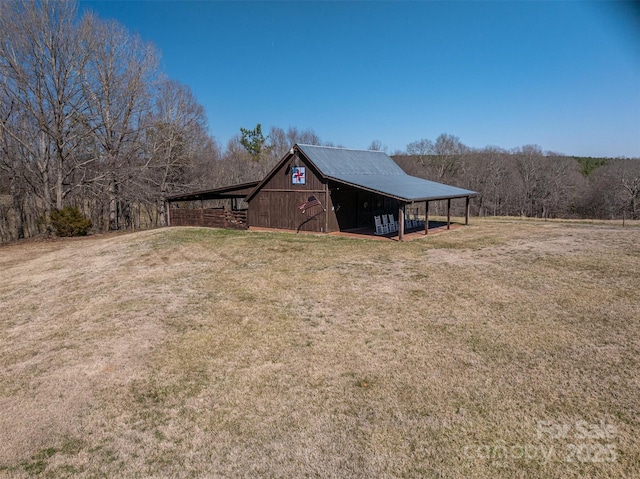 view of home's exterior with an outbuilding, a yard, metal roof, and a barn