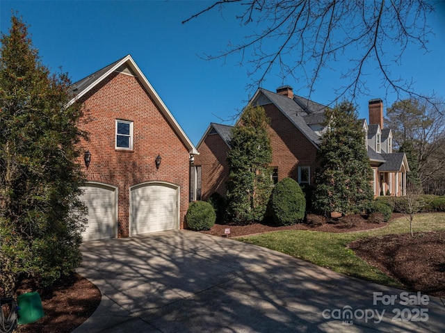 view of front facade with brick siding, driveway, a chimney, and an attached garage