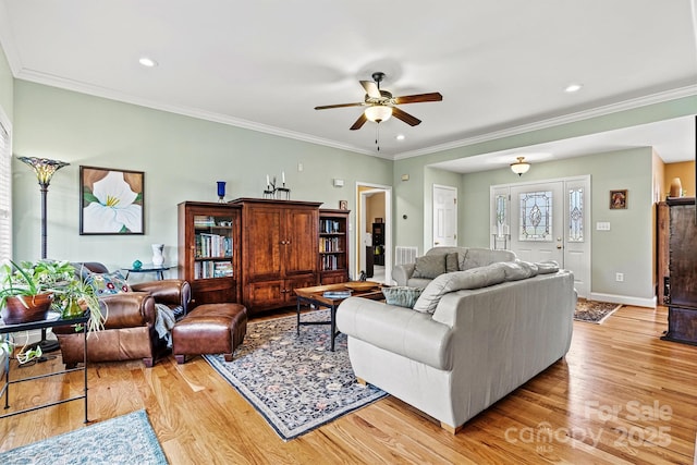 living room with light wood-style flooring, baseboards, ceiling fan, and crown molding