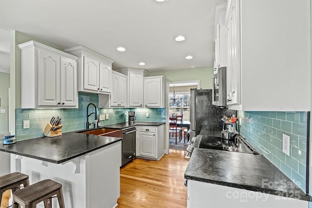 kitchen featuring stainless steel appliances, dark countertops, a peninsula, and a breakfast bar