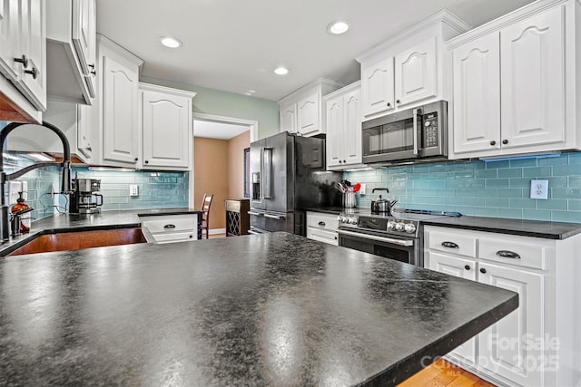 kitchen featuring dark countertops, white cabinetry, stainless steel appliances, and a sink