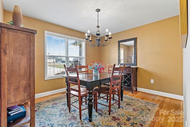 dining space featuring an inviting chandelier, light wood-style floors, and baseboards