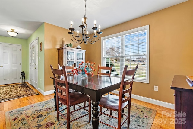 dining area with baseboards, light wood-style floors, and a chandelier