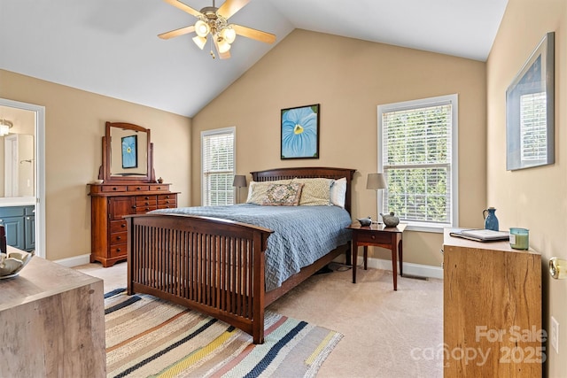 bedroom featuring baseboards, ceiling fan, vaulted ceiling, ensuite bathroom, and light colored carpet