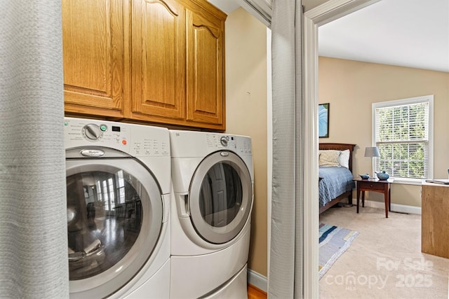 laundry area featuring separate washer and dryer, cabinet space, baseboards, and light carpet