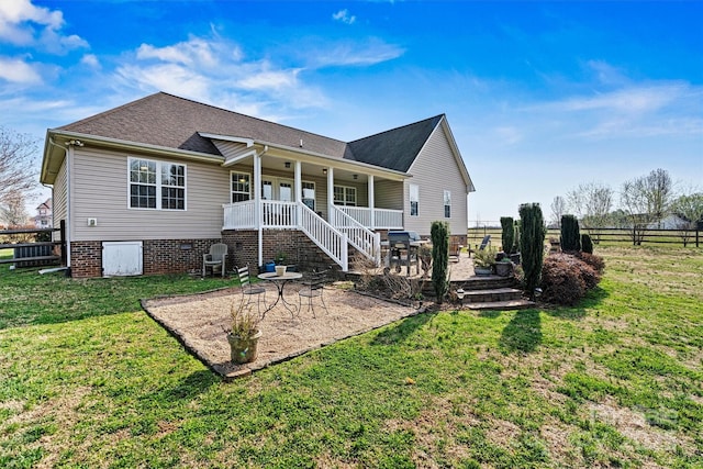 rear view of house with a yard, a patio, covered porch, and fence