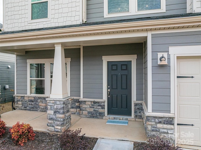 property entrance featuring a garage, stone siding, and a porch