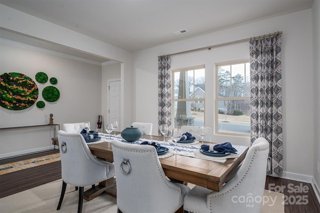 dining area featuring crown molding, wood finished floors, visible vents, and baseboards