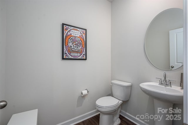 half bath featuring toilet, baseboards, and wood finished floors